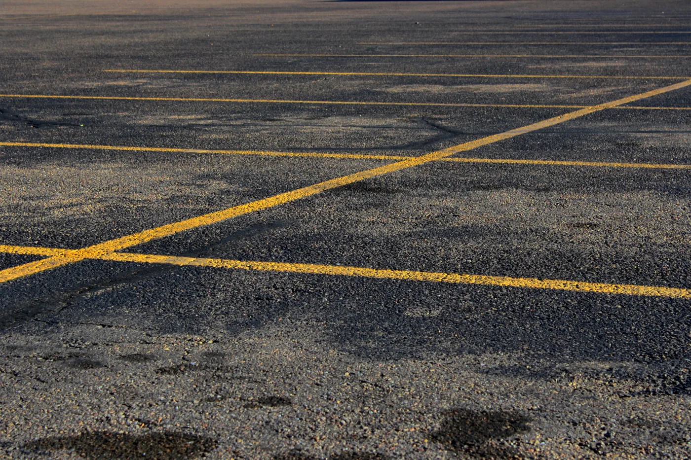 Empty asphalt parking lot with yellow parking-space lines